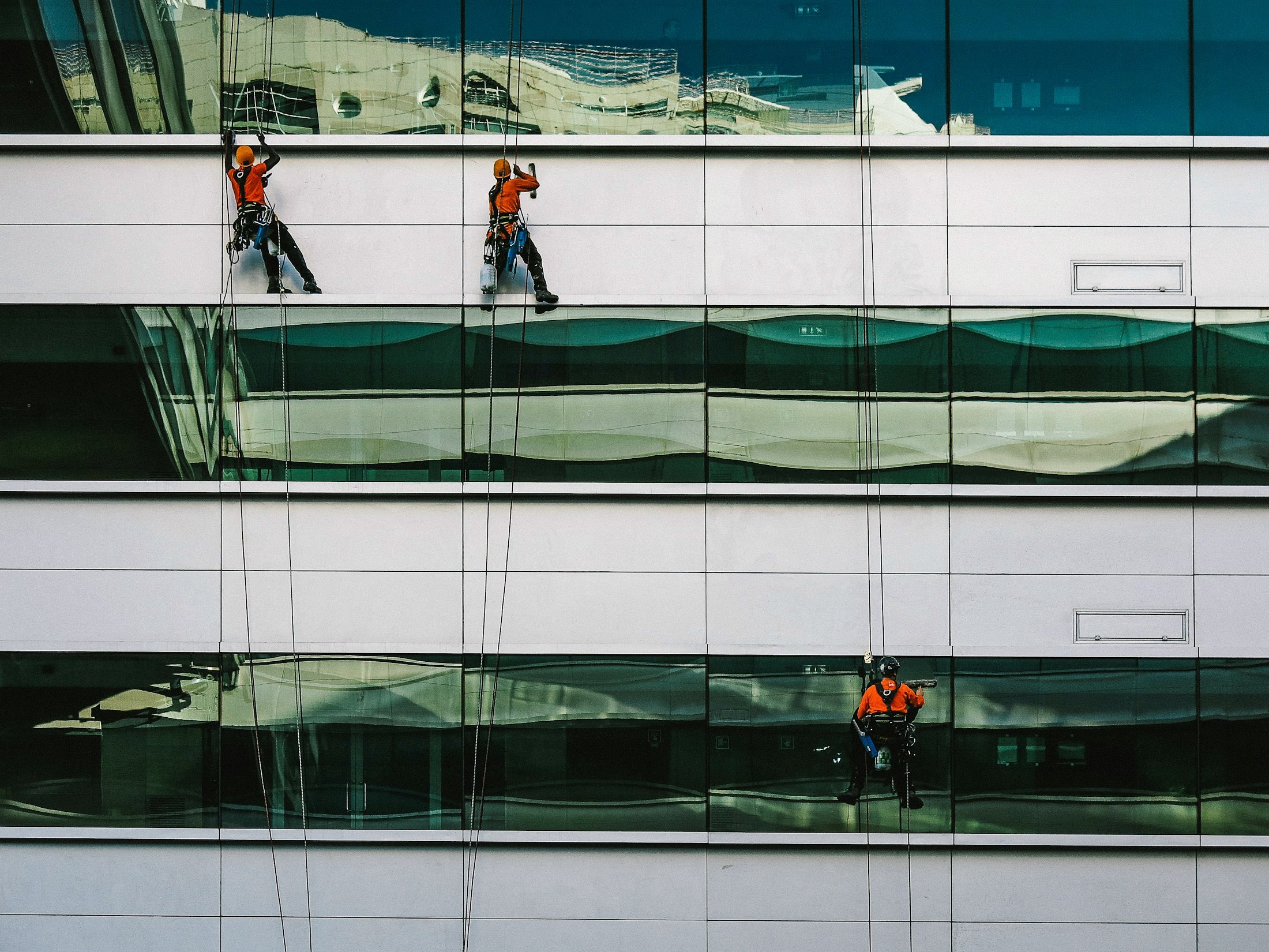 Deux vitriers en équipe sur la façade vitrée d'un immeuble de bureaux